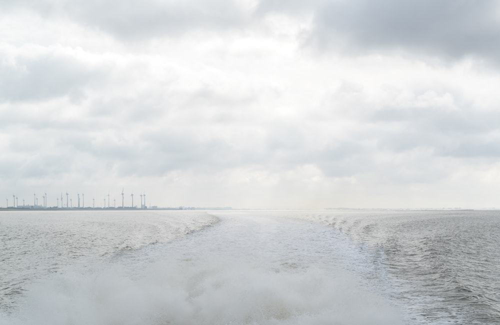 sea waves crashing on shore under white clouds during daytime