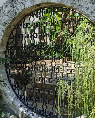 Custom metal gate with intricate design opening to a lush garden patio.