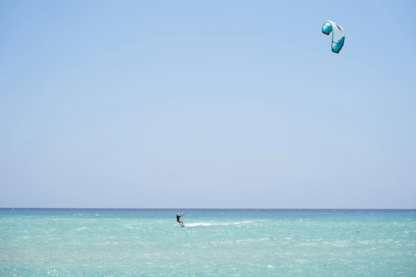 Person stand-up paddleboarding on calm turquoise water in Jambiani