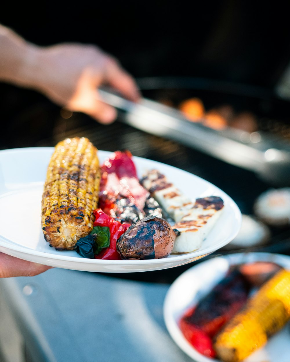 person holding stainless steel fork with grilled meat on white ceramic plate
