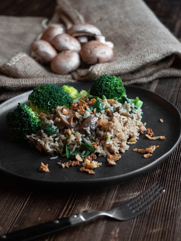 Cooked rice with broccoli on black plate