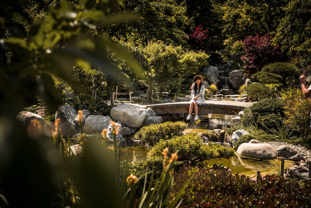 woman in black tank top and blue denim jeans standing on gray rock near body of near near near near