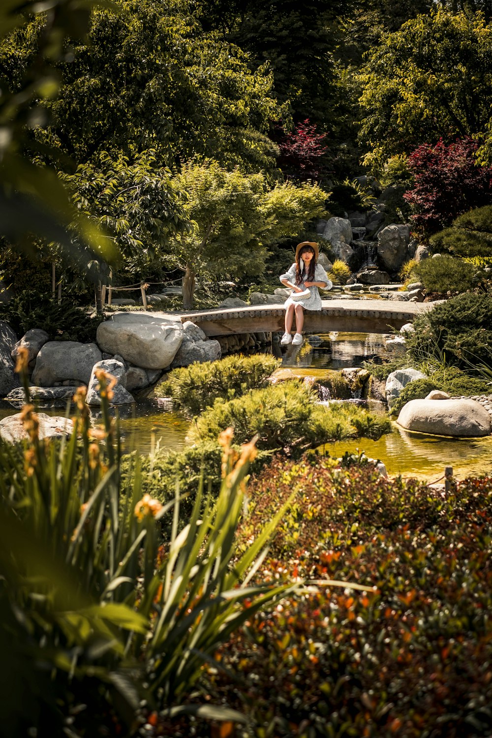 woman in blue dress sitting on rock in front of water fountain
