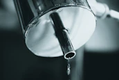 Close-up of plumber repairing a leak under a kitchen sink.