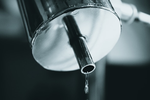 Close-up of a dripping faucet being repaired by a plumber's hands.