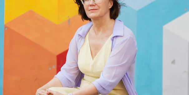 woman in white long sleeve shirt and pink cardigan sitting on concrete floor