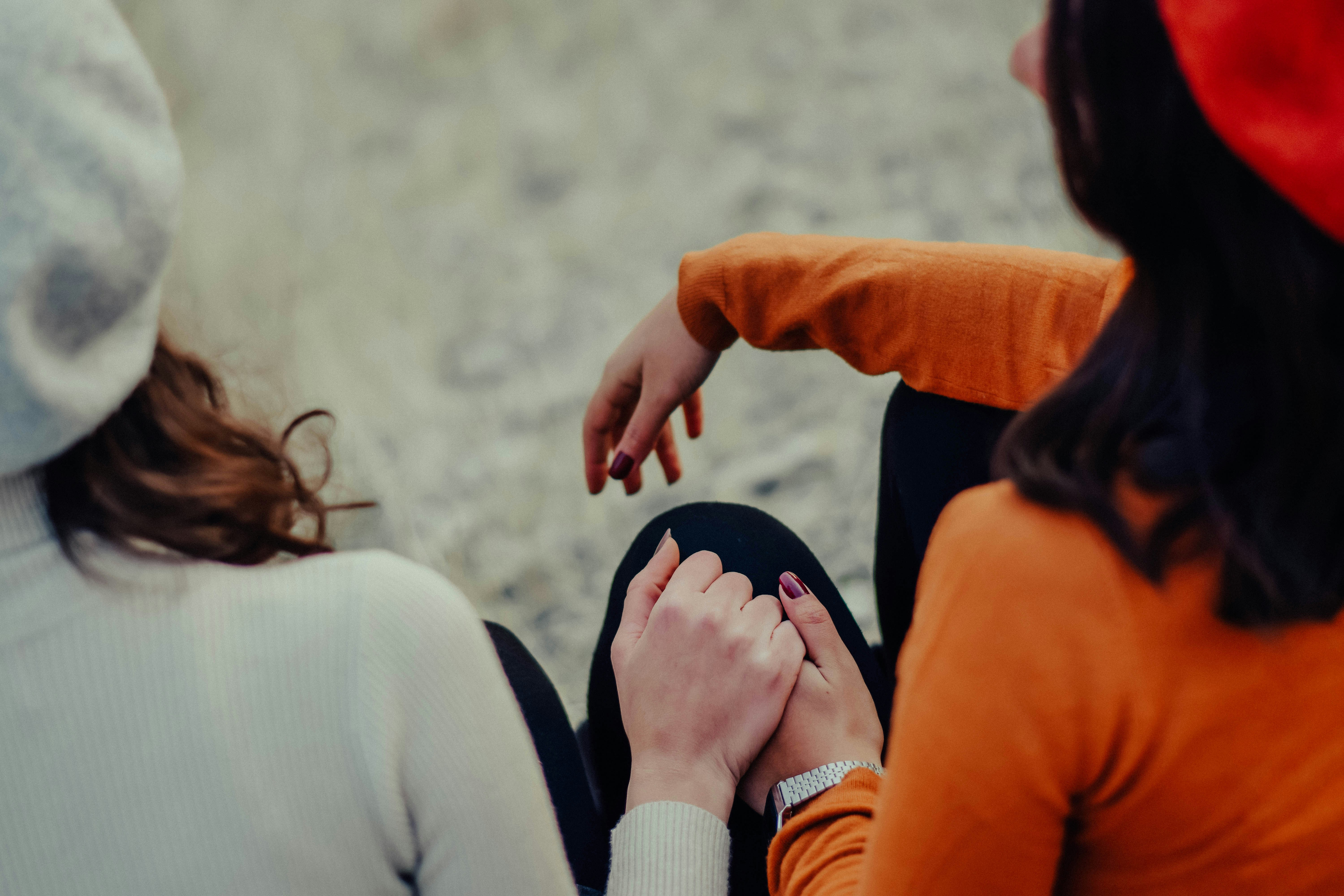 woman in orange long sleeve shirt holding another woman's hand