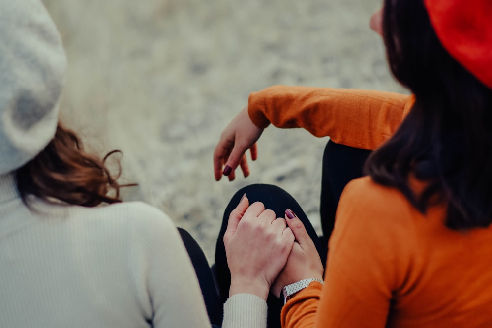 woman in orange long sleeve shirt holding womans hand