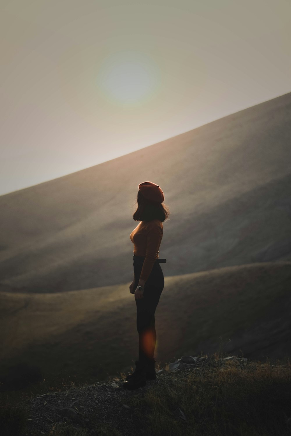 woman in black tank top and black leggings standing on gray sand during daytime