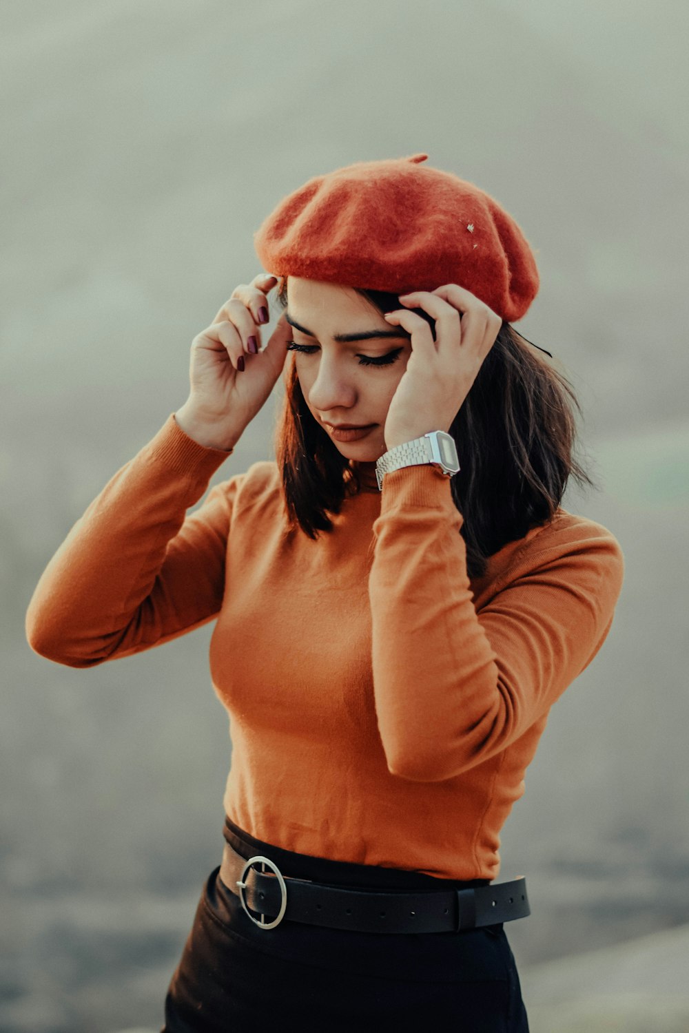 femme en chemise orange à manches longues couvrant son visage avec ses mains