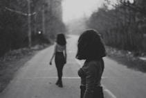 woman in black jacket walking on road during daytime