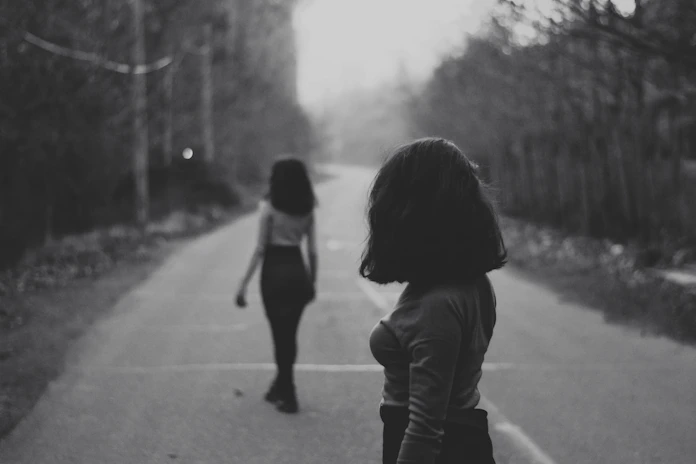 woman in black jacket walking on road during daytime