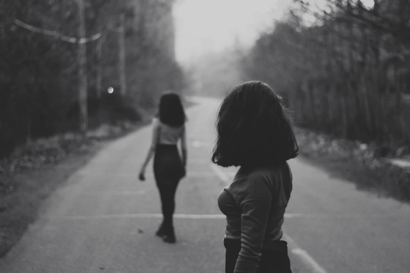 woman in black jacket walking on road during daytime