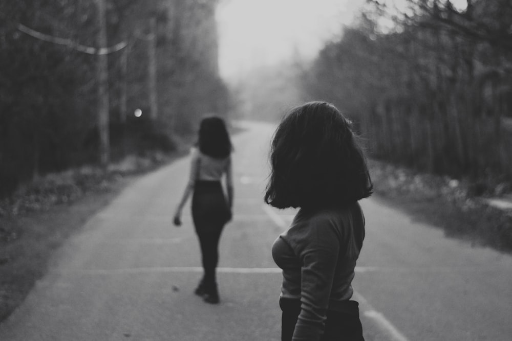 woman in black jacket walking on road during daytime