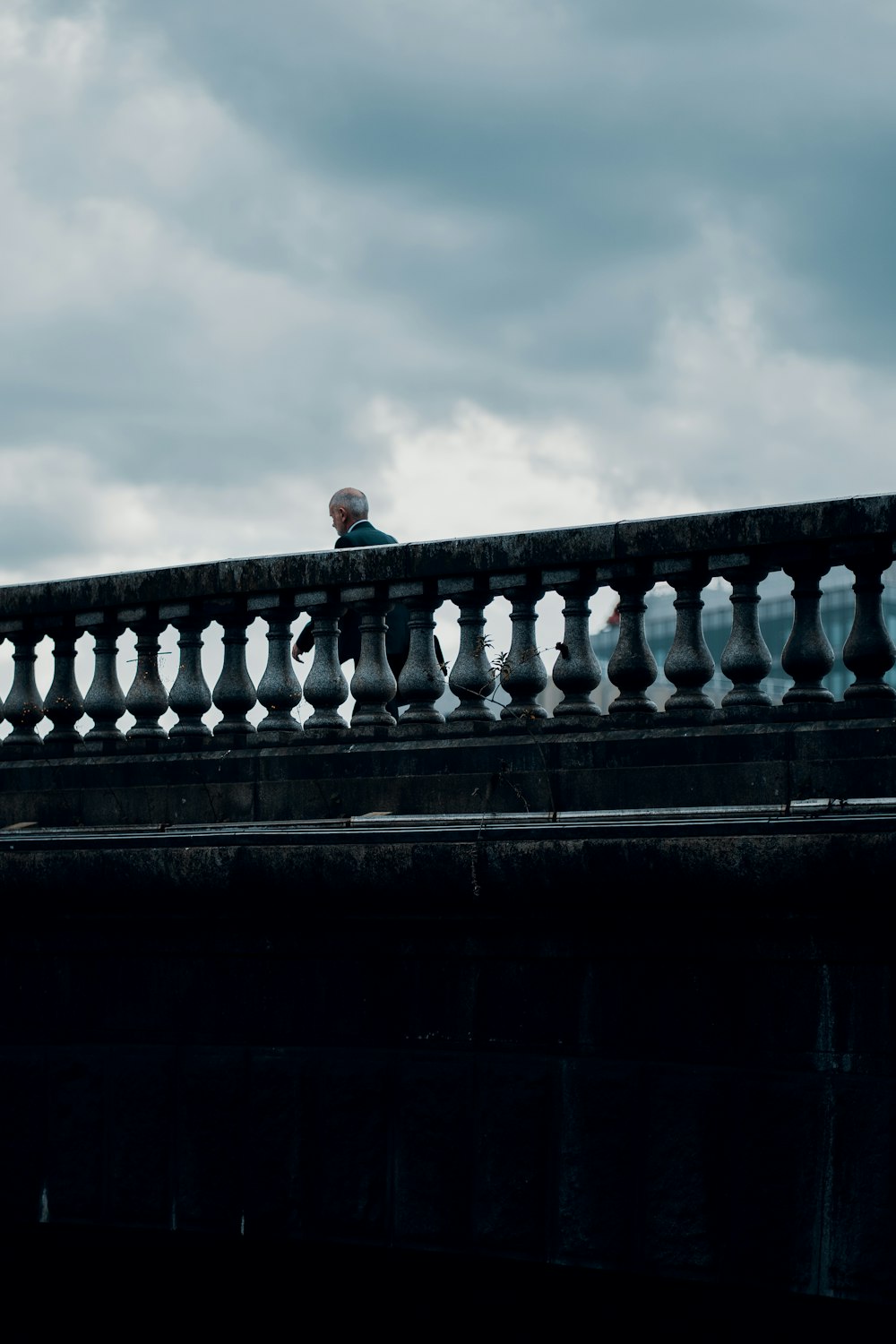 man in black jacket standing on concrete bridge during daytime