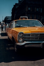 A neat yellow taxi parked outside a charming Dundee street with historic buildings in the background.