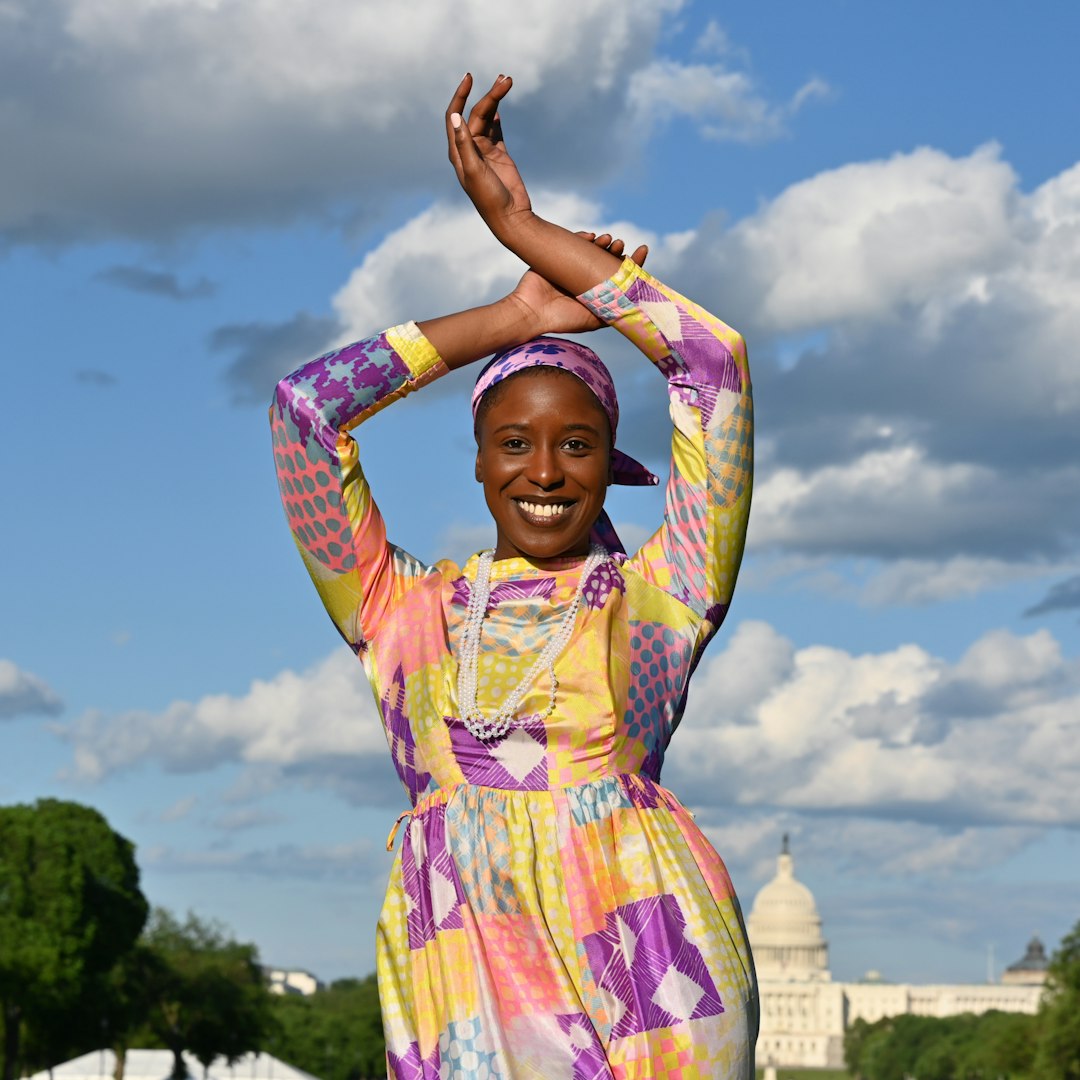 woman in pink and yellow dress raising her hands