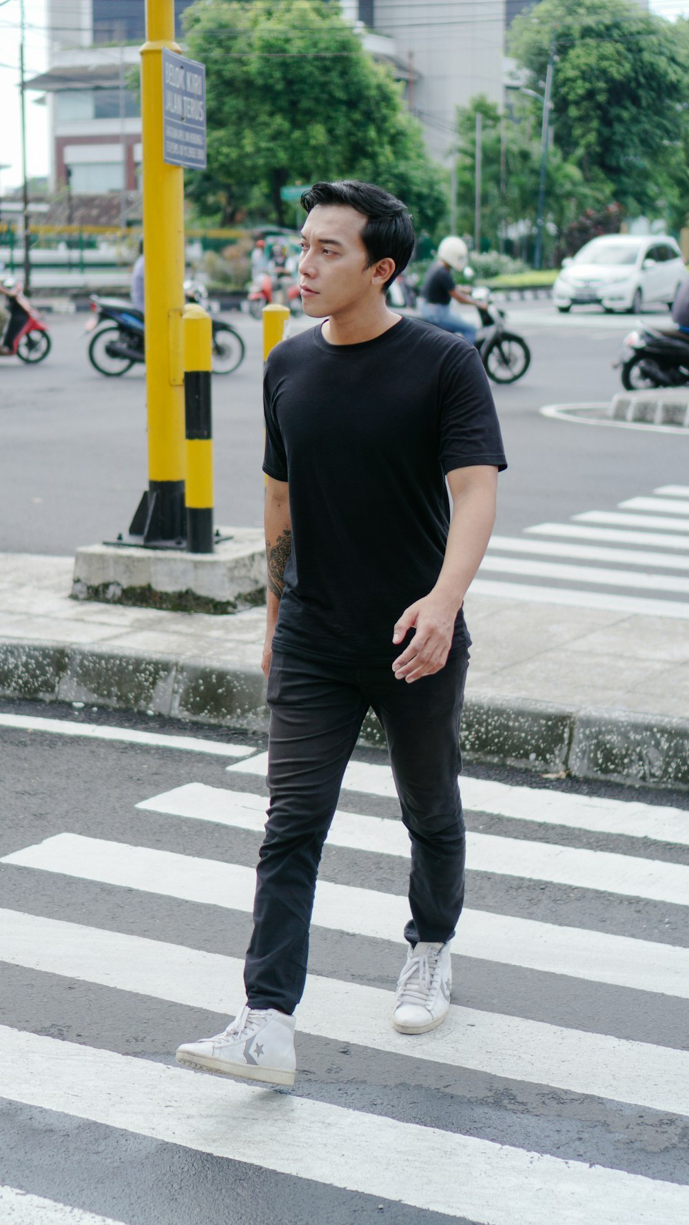 man in black crew neck t-shirt and black pants standing on sidewalk during daytime