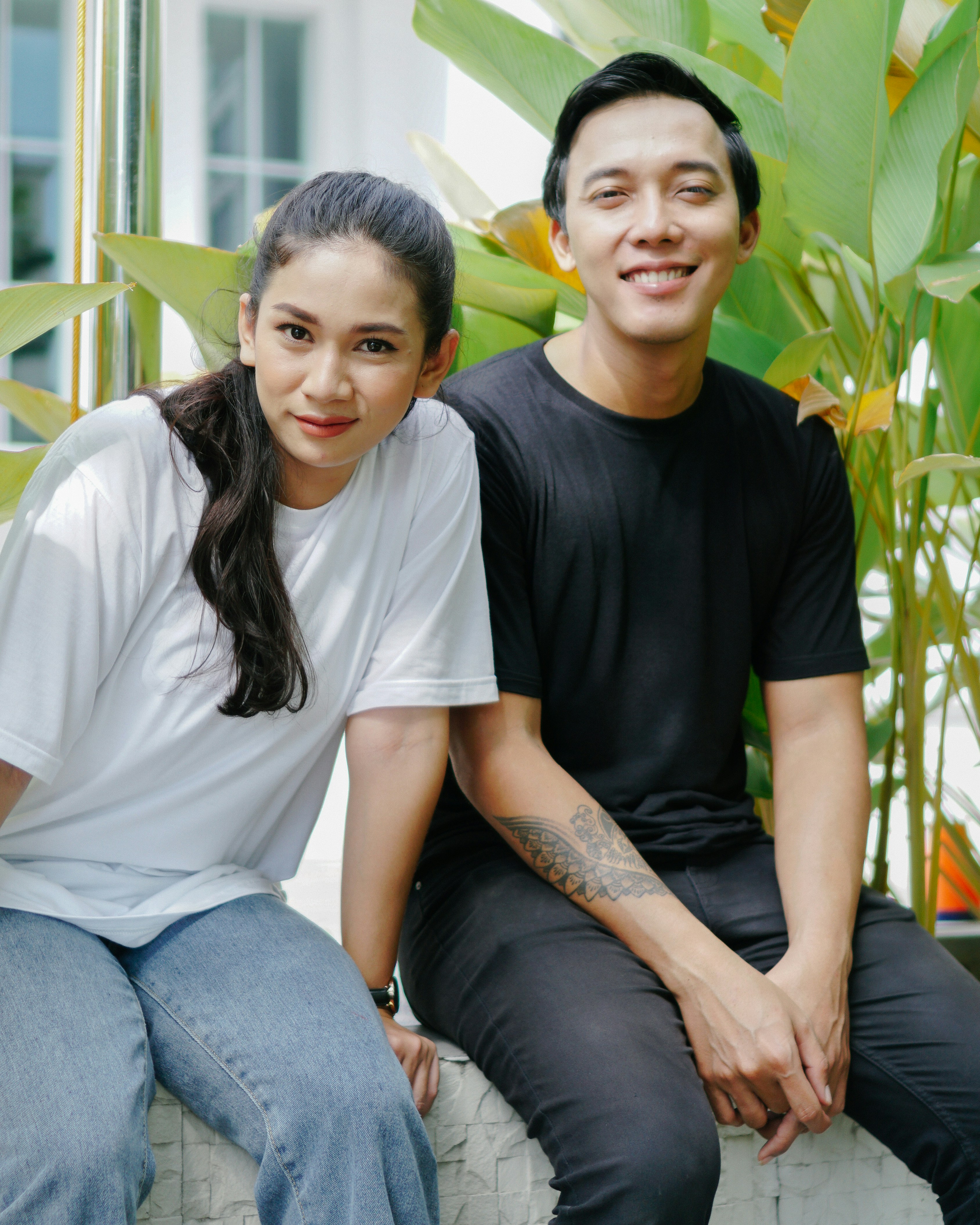 Wanita dengan kaos leher kru putih dan jeans denim biru duduk di bangku kayu coklat
