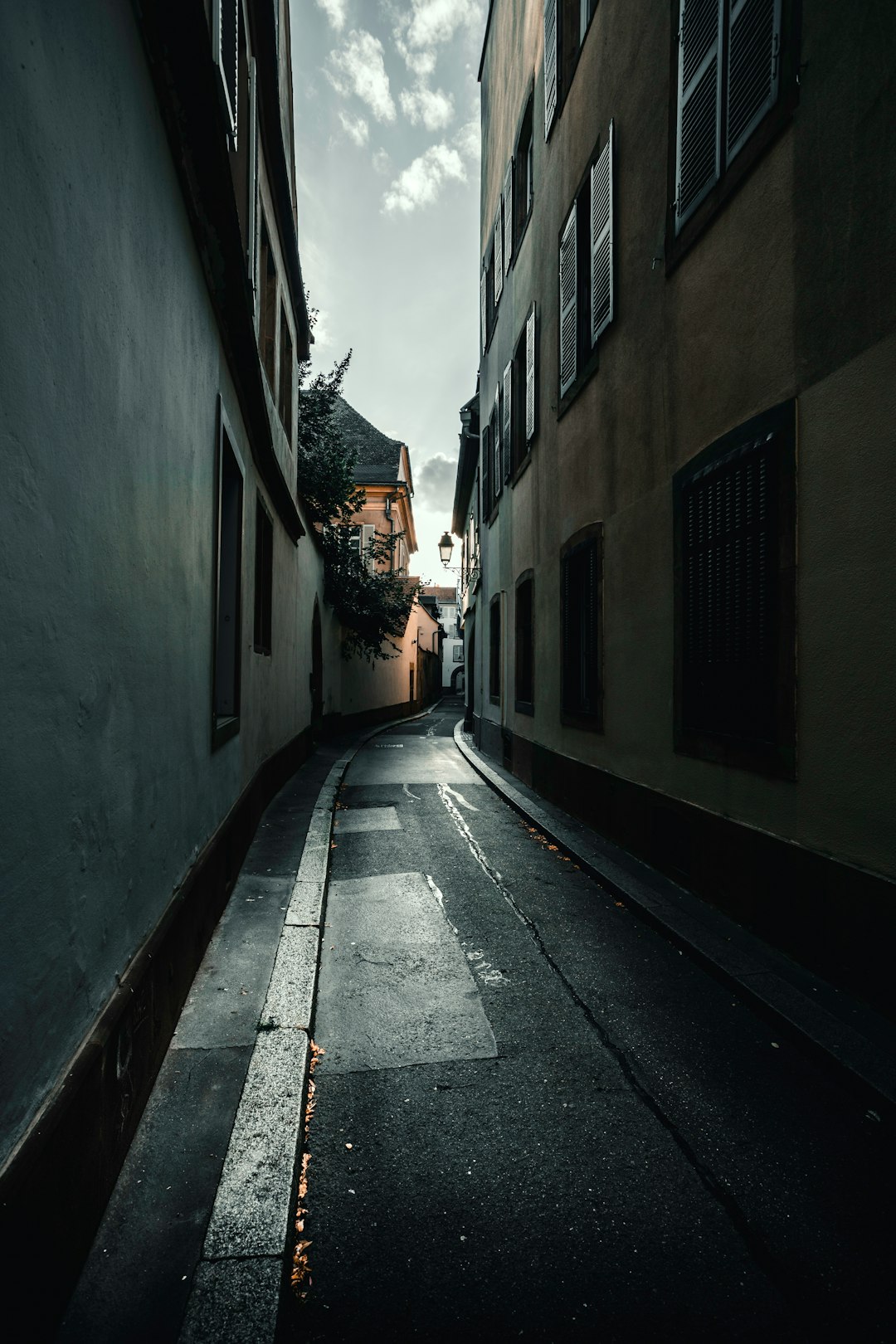 empty street in between of concrete buildings during daytime