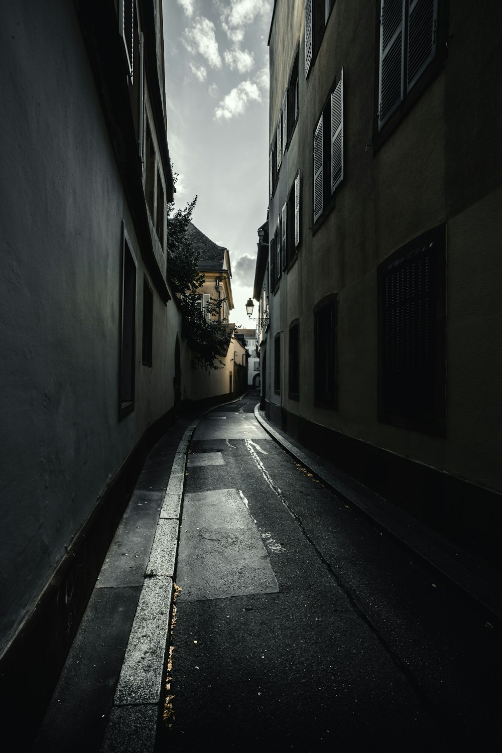 empty street in between of concrete buildings during daytime