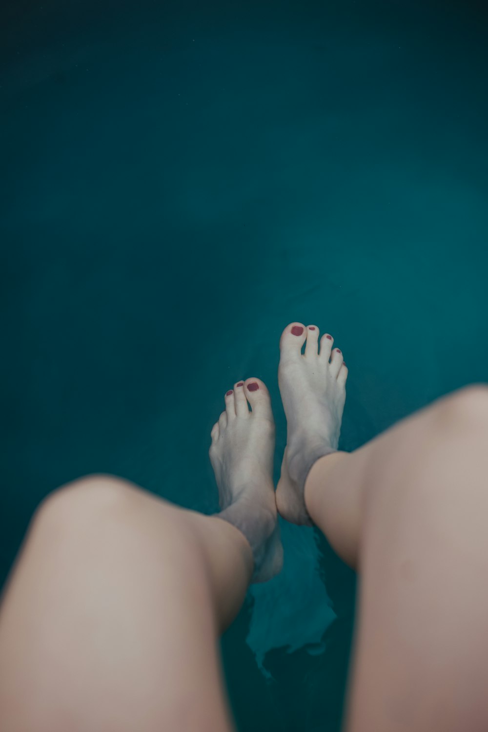 persons feet on blue water
