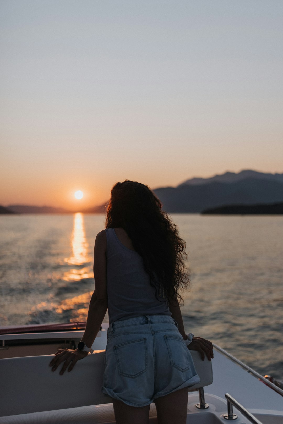 woman in white shirt sitting on brown wooden bench during sunset