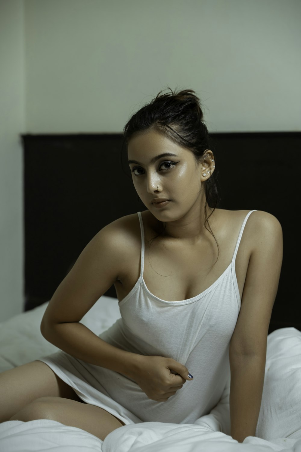 woman in white tank top sitting on bed