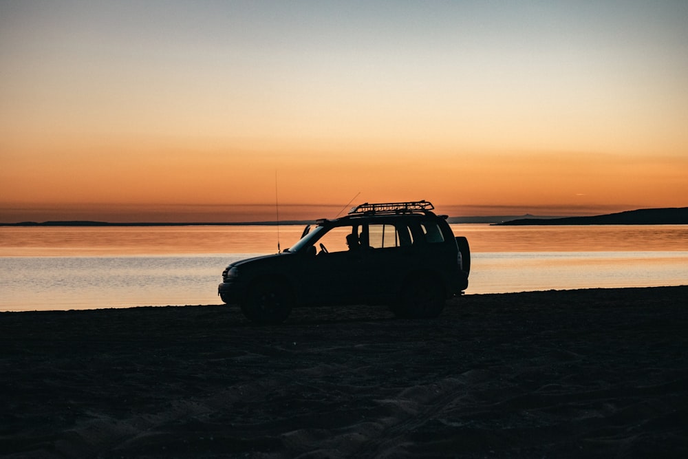 black suv on beach during sunset