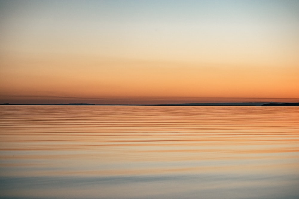 calm sea under orange sky during sunset