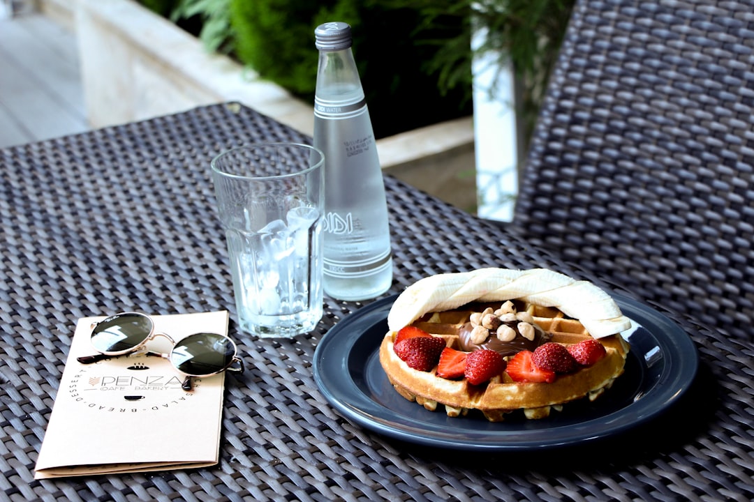 sliced bread on white ceramic plate beside clear drinking glass on black table