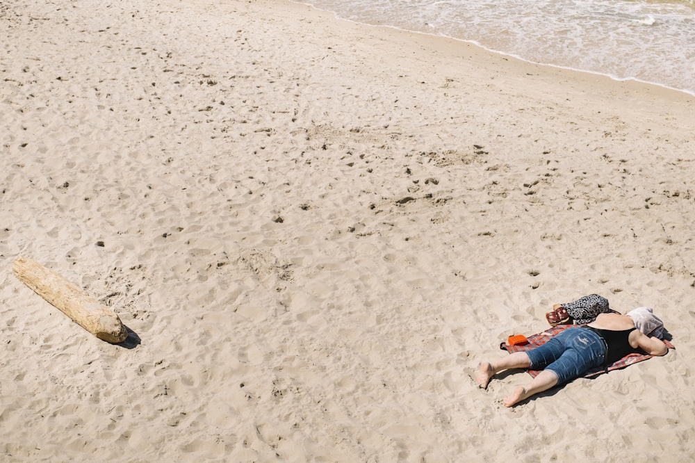 昼間、ビーチの砂浜に横たわるブルーデニムのショートパンツを着た女性