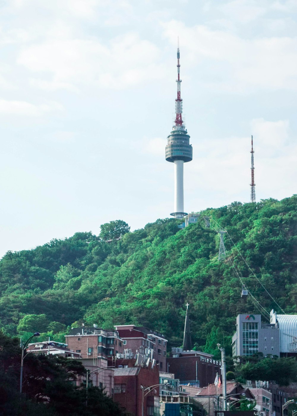 weißer und roter Turm in der Nähe grüner Bäume tagsüber