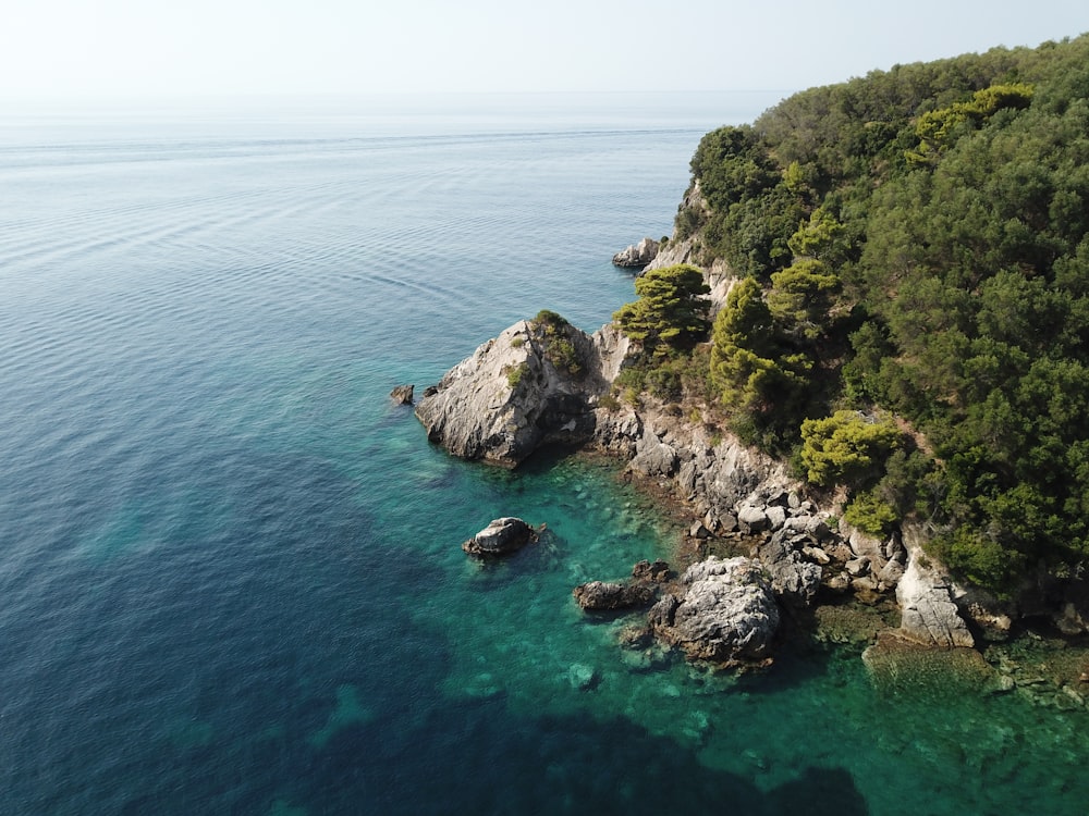 green and brown rock formation on blue sea water during daytime