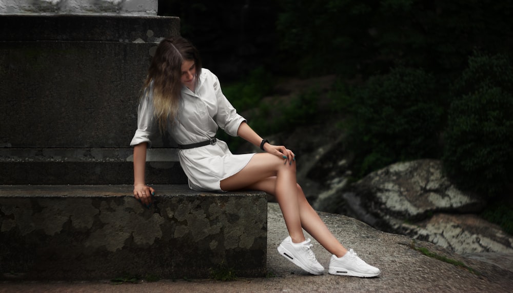 woman in white dress shirt sitting on concrete bench