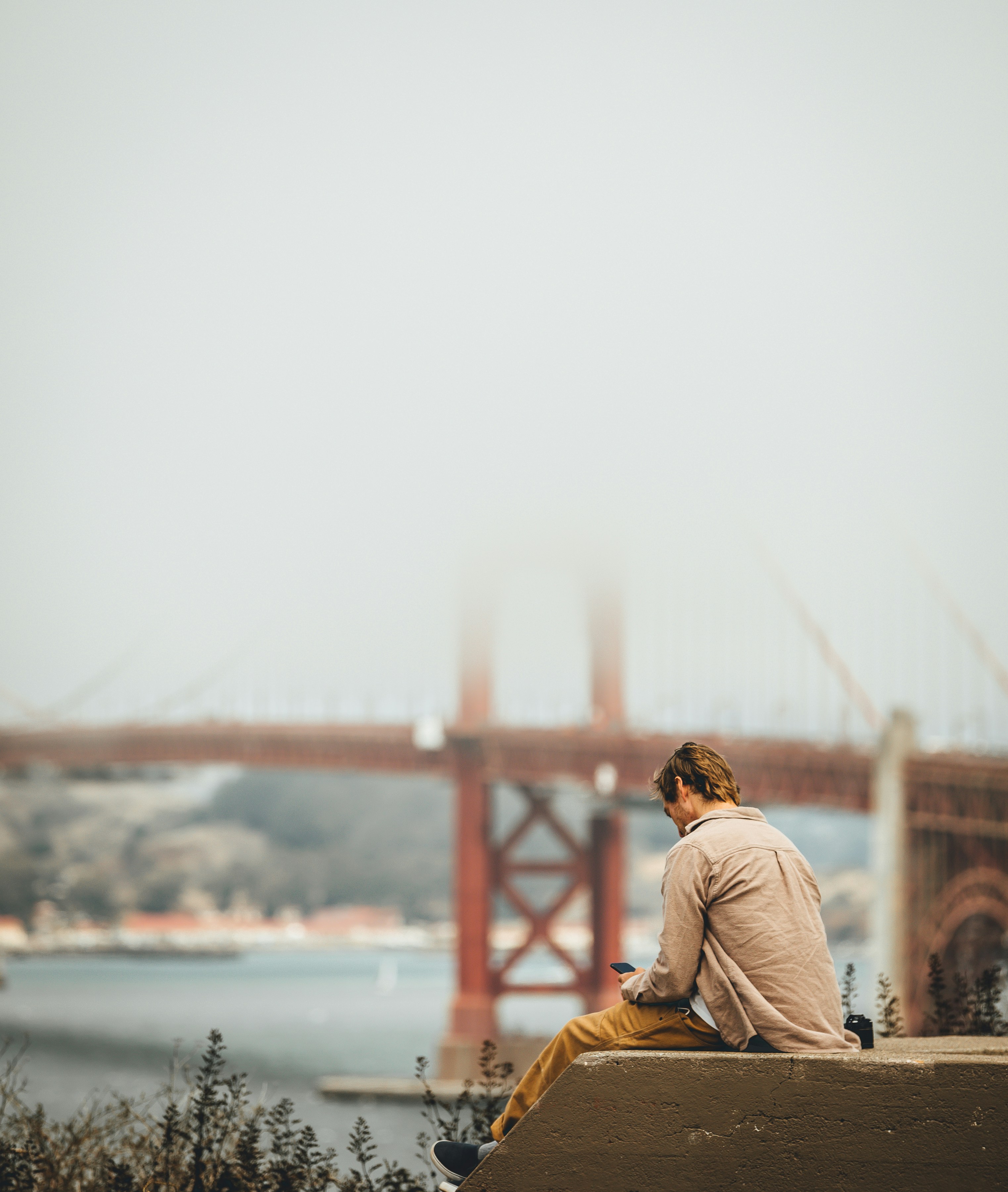 man in white long sleeve shirt sitting on brown wooden dock during daytime