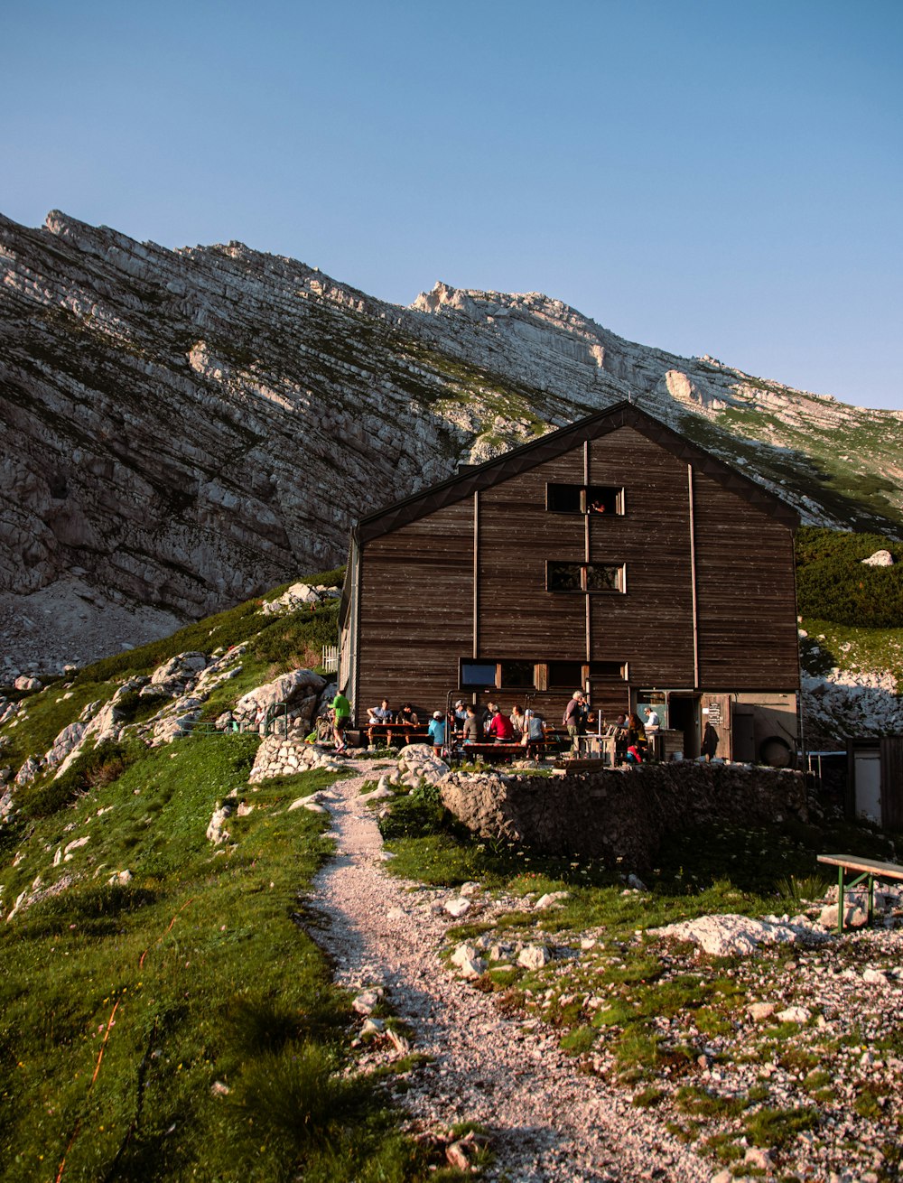 Casa di legno marrone sul campo di erba verde vicino alla montagna rocciosa durante il giorno