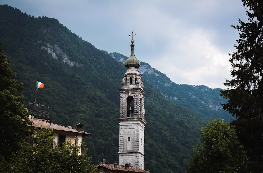 brown and white concrete church near green mountain under white clouds during daytime