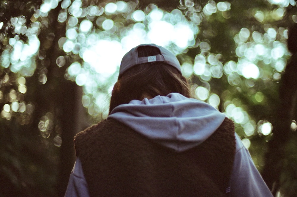 person in purple hoodie standing near trees during daytime