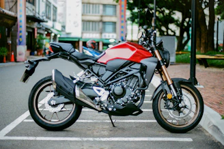 red and black naked motorcycle parked on the street during daytime