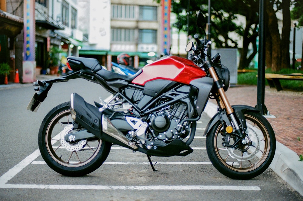 red and black naked motorcycle parked on the street during daytime