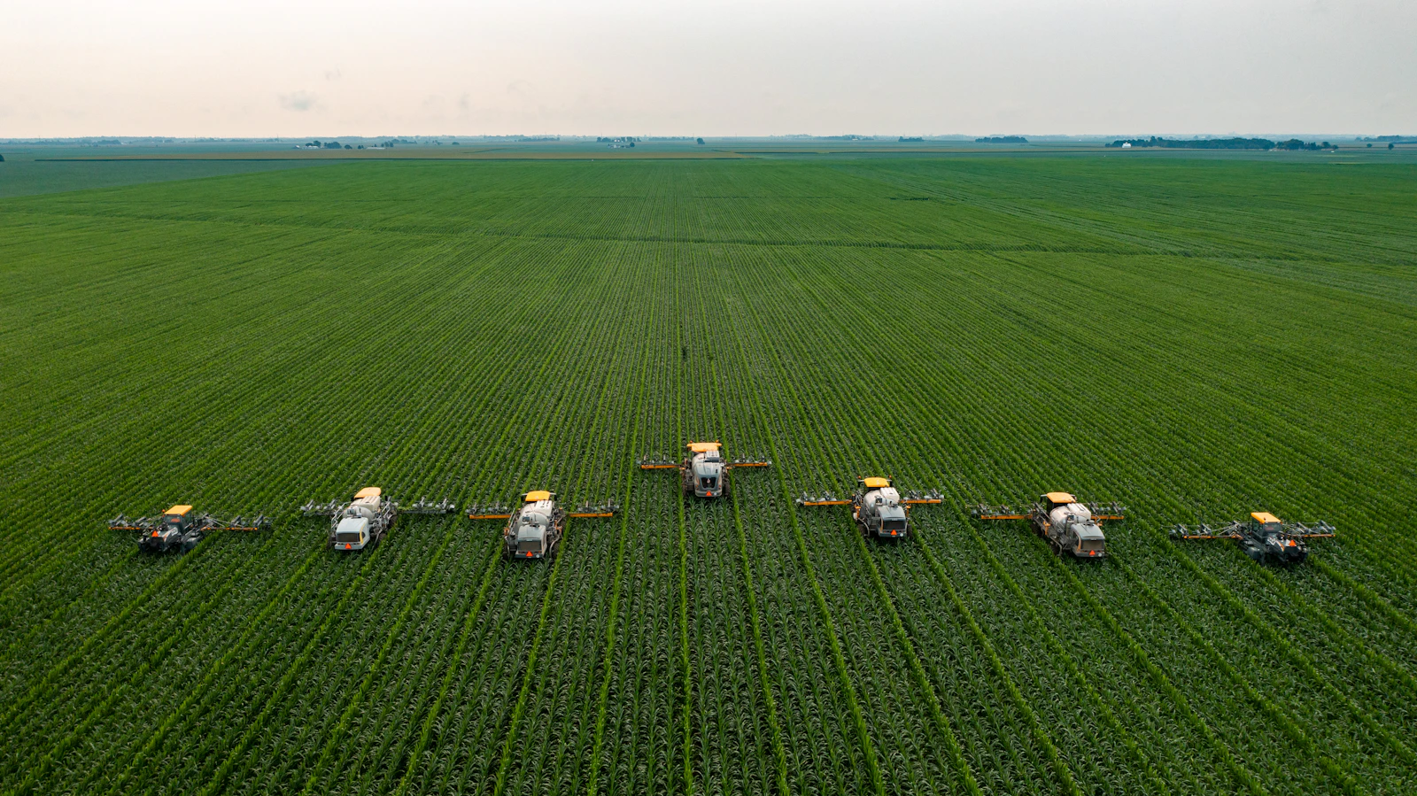 Aerial view of a row of machines working a green field
