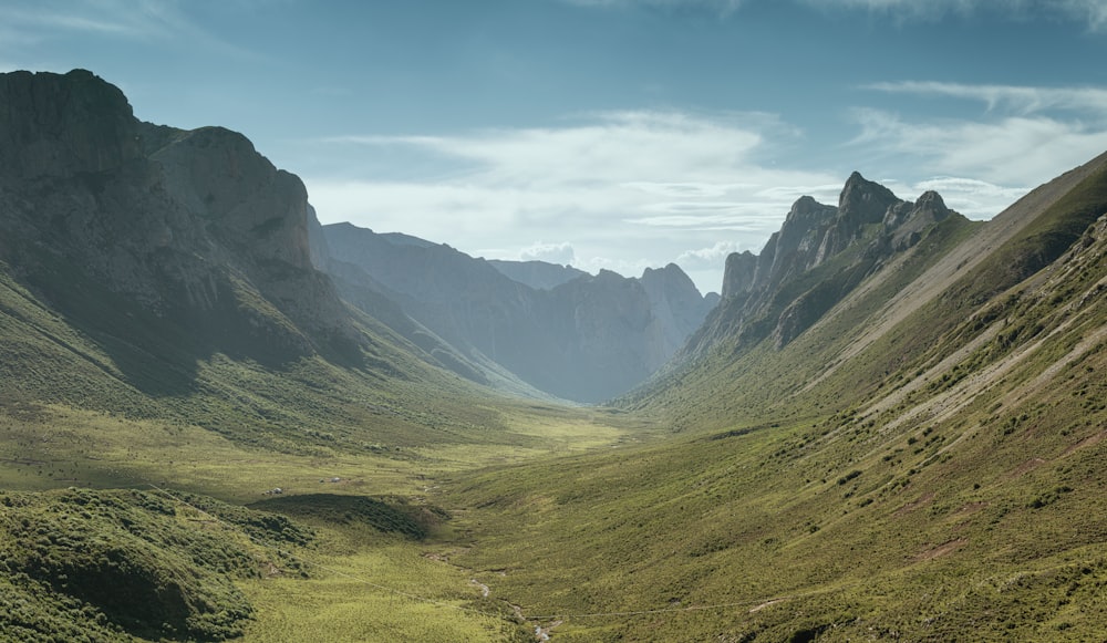 green grass field and mountains under blue sky during daytime