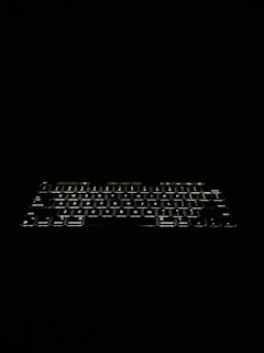 A compact wireless keyboard with illuminated keys glowing gently in low light.