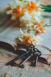 white and yellow flower on book page with four keys laying on the end of the page.