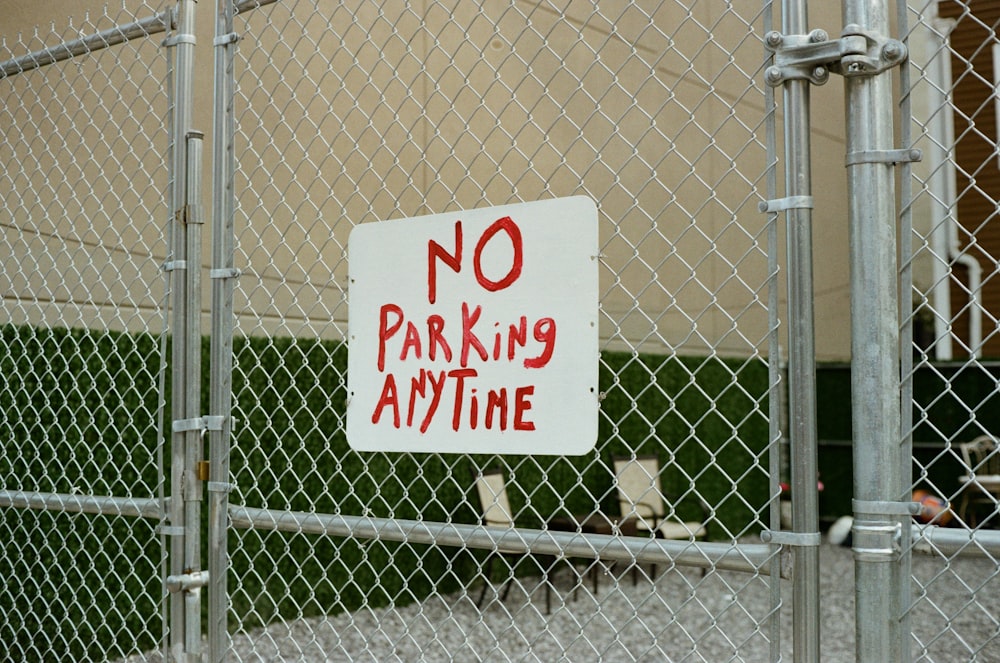 a no parking sign on a chain link fence