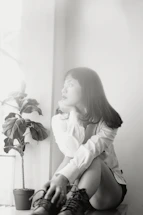 A serene woman sitting peacefully by a window, reflecting on her next steps.