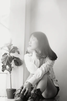 A serene woman sitting peacefully by a window, reflecting on her next steps.