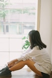 woman in white long sleeve shirt sitting on white floor tiles