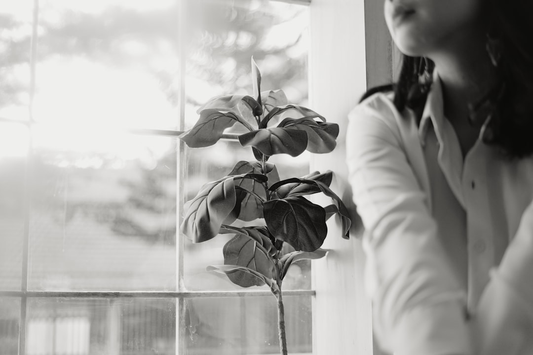 grayscale photo of a woman in white coat holding a plant